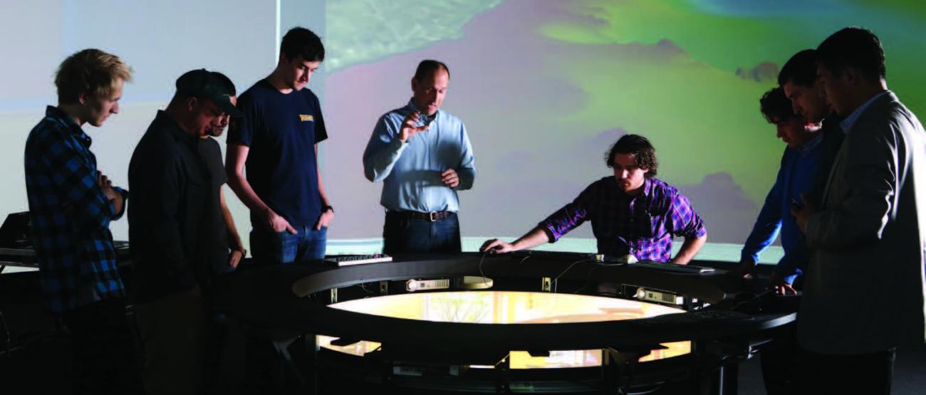 Group of people in the Cognitive and Immersive Systems Lab fathered around the "Situations Room”.