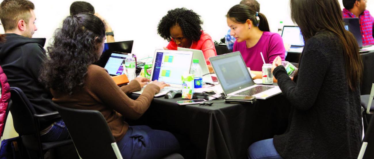 A group of people around a table with laptops. 